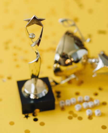 A silver trophy and confetti on a yellow background.