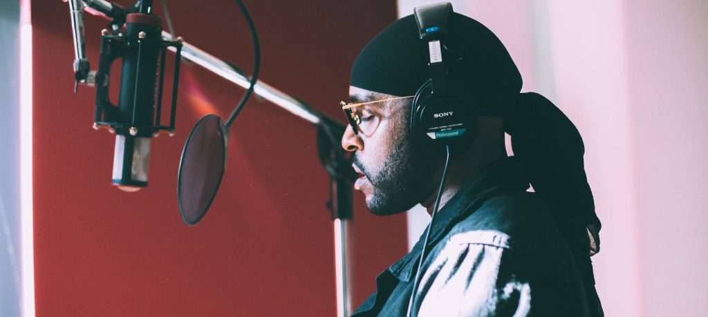 A man wearing a hat and headphones in a recording studio.