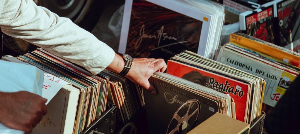 A person picking up vinyl records at a flea market.