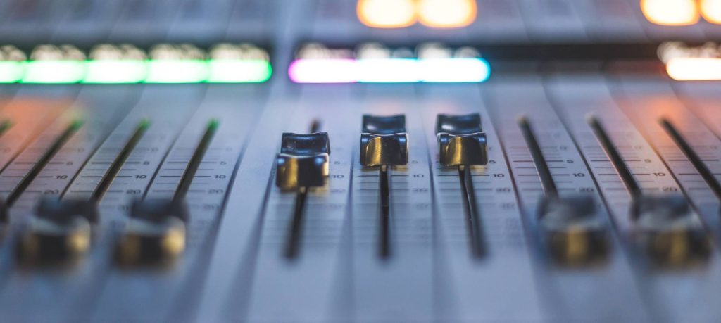 A close up of a mixing board in a recording studio.