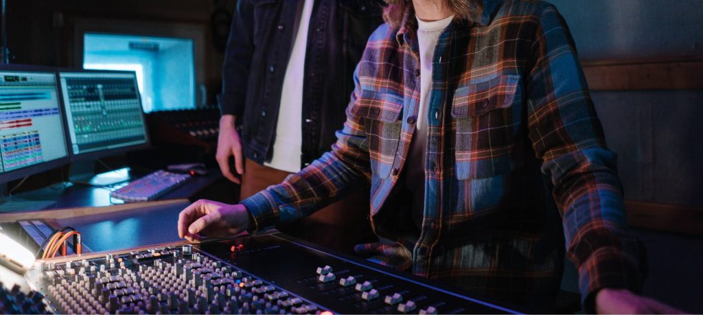 Two people in front of a mixing board in a recording studio.