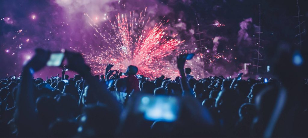 A crowd of people watching fireworks at a music festival.